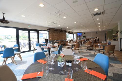 a dining room with tables and chairs and windows at The Originals City, Hôtel de la Confluence, Agen Ouest in Damazan
