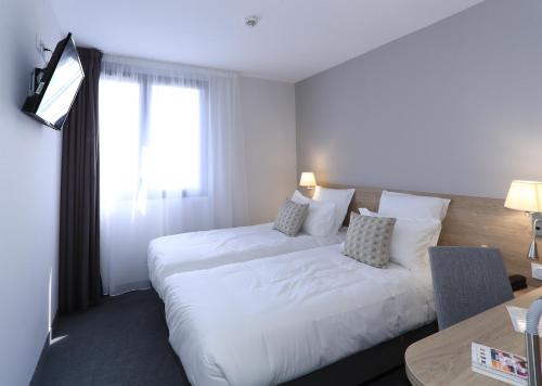a hotel room with two beds and a window at The Originals City, Hôtel de la Confluence, Agen Ouest in Damazan
