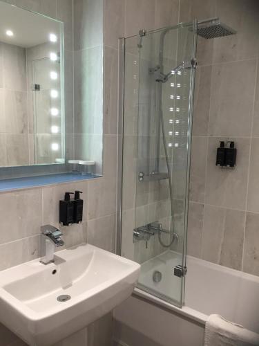 a bathroom with a sink and a glass shower at Hythe Imperial Hotel, Spa & Golf in Hythe
