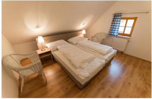 ein Schlafzimmer mit einem Bett, einem Stuhl und einem Fenster in der Unterkunft Apartmány Nová Pec in Nová Pec