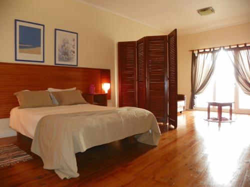 a bedroom with a large bed and a large window at A Casa do Lado in Horta