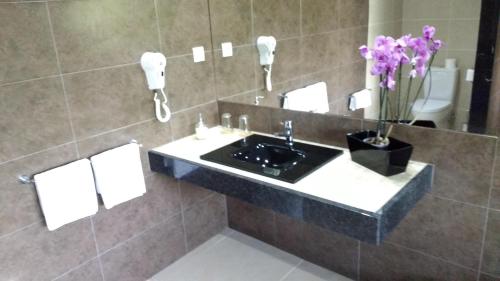 a bathroom with a sink and a mirror and flowers at Casa Do Prado Guesthouse in Vila Real