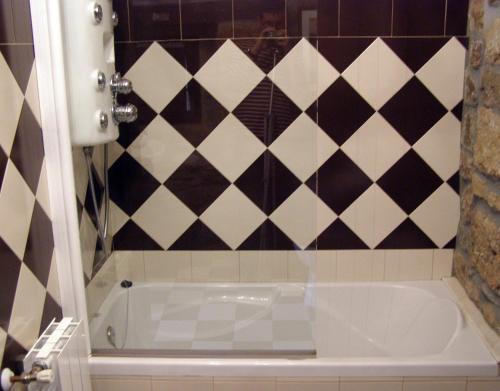 a bathroom with a tub and a tiled wall at Posada Rural Ochohermanas in Las Fraguas