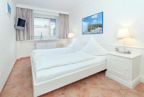ein weißes Schlafzimmer mit einem Bett und einem TV in der Unterkunft Wohnung Anker in Westerland