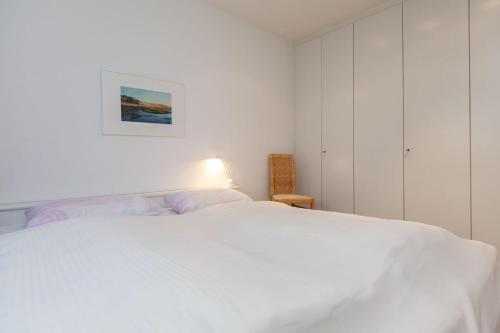 ヴェスターラントにあるFerienwohnung-Finlandiaの白いベッドルーム(白いベッド1台、ランプ付)