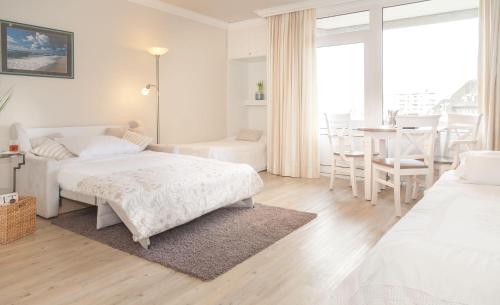 ヴェスターラントにあるSylter-Kajuete-Haus-Ornumの白いベッドルーム(ベッド2台、テーブル、椅子付)