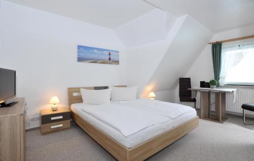 Schlafzimmer mit einem weißen Bett und einem TV in der Unterkunft Wohnung Sylthome in Westerland