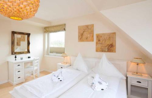 a white bedroom with a large bed with white pillows at Meerwievke in Tinnum