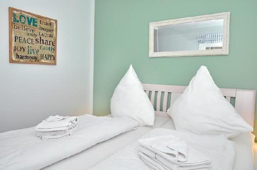 ヴェスターラントにあるSylter-Bernsteinの白い枕と鏡付きの白いベッド