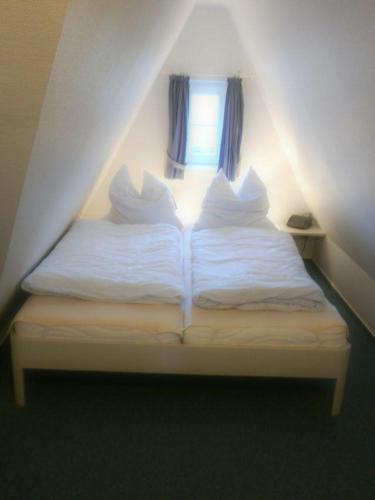 uma cama com lençóis brancos e almofadas num quarto em Westhof-7 em List