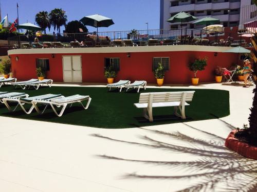 a group of lounge chairs and a building with umbrellas at Apartamentos Amazonas in Playa del Ingles
