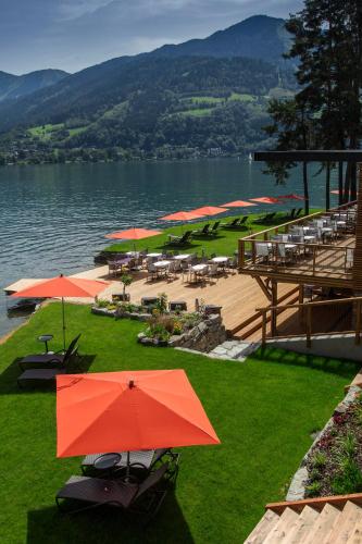 a resort with tables and umbrellas and a lake at Seevilla Freiberg in Zell am See