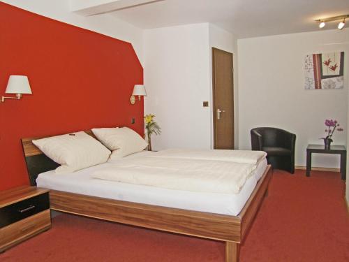 ein Schlafzimmer mit einem großen Bett mit einer roten Wand in der Unterkunft Hotel Beller in Kenzingen