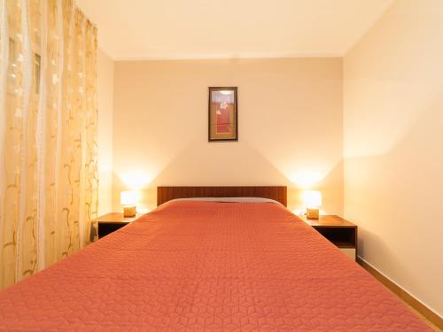 a bedroom with a large red bed with two lamps at Apartments Spin in Budva
