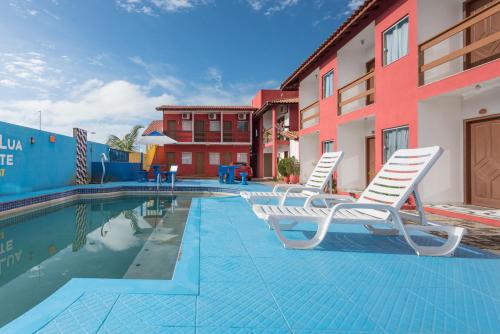 - une piscine avec 2 chaises longues à côté d'un bâtiment dans l'établissement Pousada Lua de Tomate, à Porto Seguro
