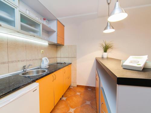 a kitchen with orange and white cabinets and a sink at Apartments Spin in Budva