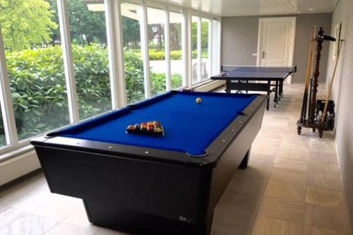 a pool table in a room with two tables at Villa Kempen-Broek in Weert