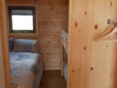 1 dormitorio con 1 cama en una cabaña de madera en Cosy Camping Suffolk en Ipswich