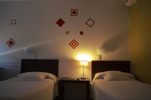 Habitación de hotel con 2 camas y reloj en la pared en Hotel La Posada del Viajero en Río Cuarto