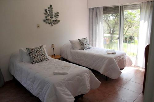 two beds in a room with a window at Mon Petit Hotel in Rosario