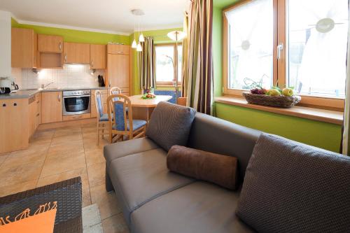 a living room with a couch and a kitchen at Appartementhaus Charisma in Fieberbrunn