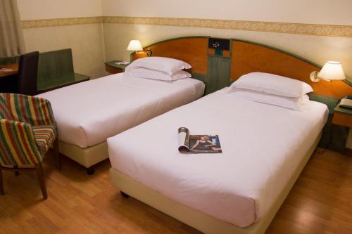 a hotel room with two beds and a chair at Best Western Plus Soave Hotel in San Bonifacio