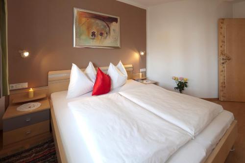 a bedroom with a large white bed with red pillows at Appartementhaus Charisma in Fieberbrunn