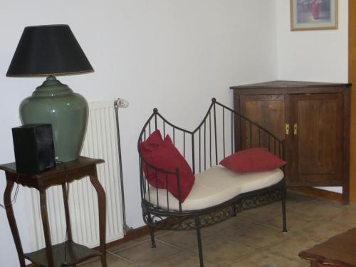 a chair with red pillows sitting next to a lamp at B&B La Grange in Durbuy