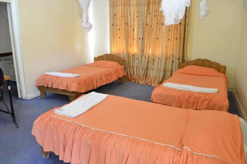 two beds in a room with orange sheets at Adventist LMS Guest House & Conference Centre in Nairobi