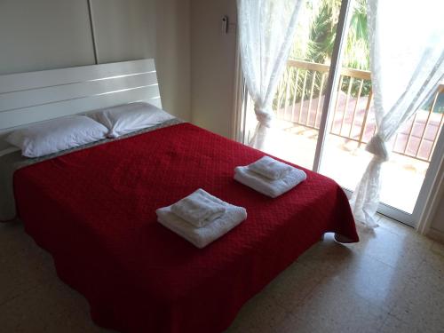 a bedroom with a red bed with two towels on it at Maria Petros Beach Houses in Perivolia