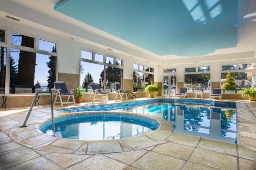 a swimming pool in a hotel lobby with windows at Huinid Pioneros Hotel & Aparts in San Carlos de Bariloche