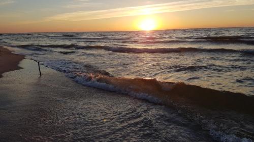 a sunset on the beach with the ocean at Dom Wypoczynkowy Oskar Jastrzębia Góra in Jastrzębia Góra