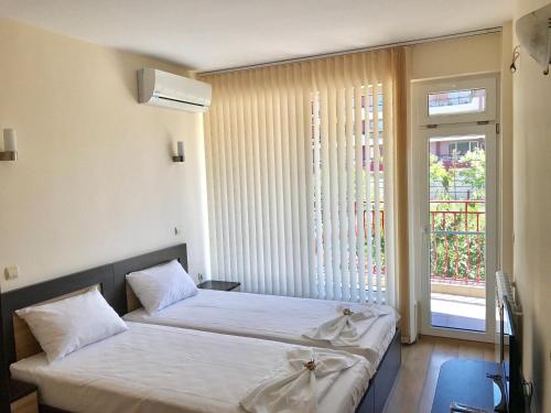 two beds in a room with a window at Jane Guest House in Nesebar