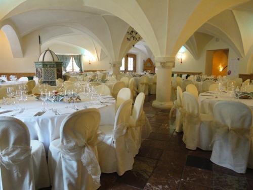 a room with white tables and chairs in a building at Hotel Edelhof in Tarvisio