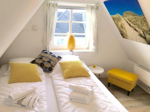 ein Schlafzimmer mit einem Bett mit gelben Kissen und einem Fenster in der Unterkunft App. Buhne in Westerland