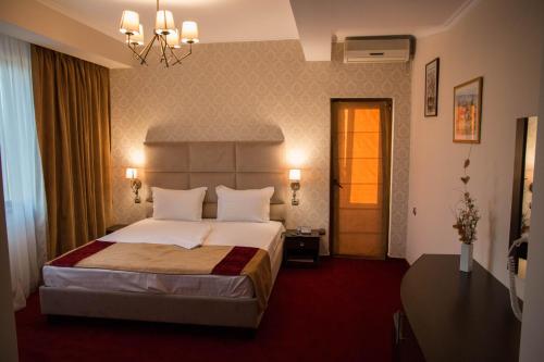 una camera d'albergo con letto e lampadario a braccio di Hotel Ioana a Constanţa