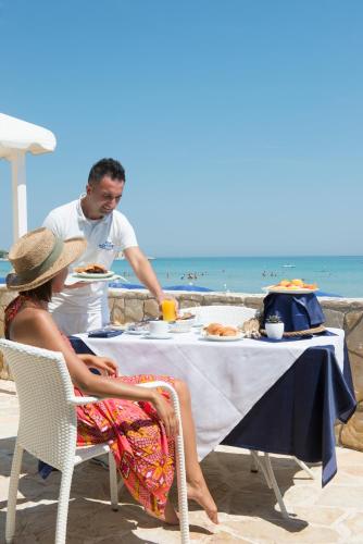 a man and woman sitting at a table on the beach at Hotel Del Levante in Torre Canne