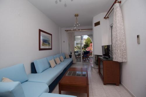 a living room with a blue couch and a tv at Alexger Gerakini Beach house view in Gerakini