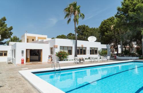 a villa with a swimming pool in front of a house at Bungalows Es Pins - Emar Hotels in Playa Migjorn