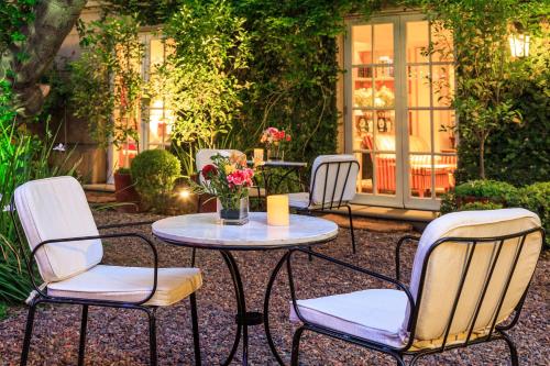 4 chaises et une table avec un vase de fleurs dans l'établissement Hotel Boutique Le Reve, à Santiago