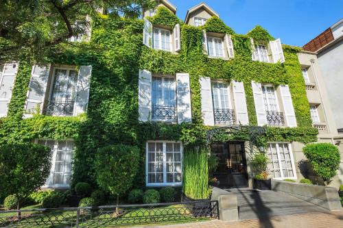 a building covered in green ivy on a street at Hotel Boutique Le Reve in Santiago