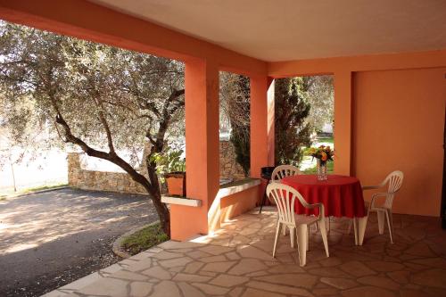 eine Terrasse mit einem Tisch, Stühlen und einem Baum in der Unterkunft Domaine Le Clos des Oliviers in Sorbo-Ocagnano