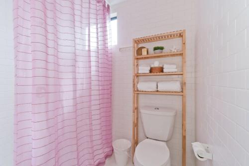a bathroom with a pink shower curtain and a toilet at Steps to the Beach, Rooftop Deck in San Diego