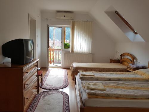a bedroom with three beds and a tv and a window at Pensiunea Lőrincz *** Panzió in Sovata