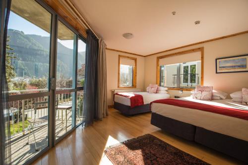 a hotel room with two beds and a balcony at Coronation Lodge in Queenstown