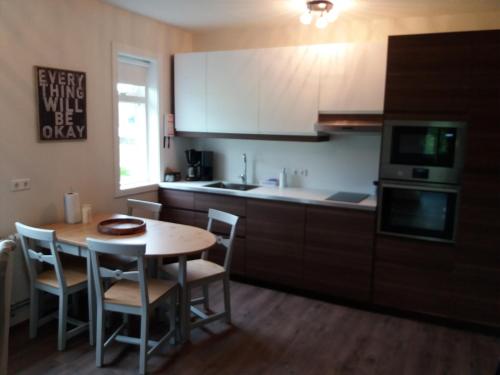 a kitchen with a table and chairs and a kitchen with white cabinets at Breidamyri Farm Apartments in Laugar