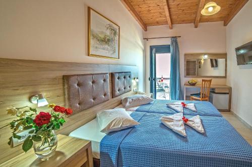 Blue Aegean Hotel & Suites في غوفي: غرفة نوم بسرير ازرق وعليها ورد احمر