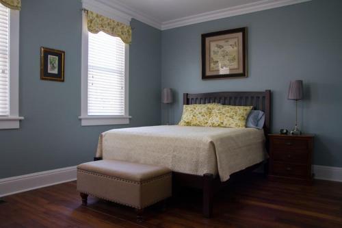 a bedroom with blue walls and a bed and a stool at Wishmaker House B&b in Bellville