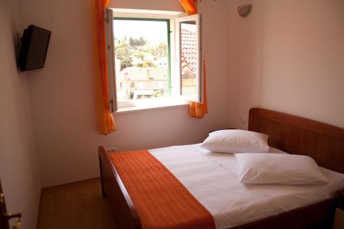 ein Schlafzimmer mit einem Bett und einem Fenster in der Unterkunft Apartments Jaksic in Postira