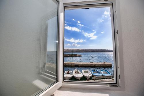 a window with a view of boats in the water at Apartmani Cindrić in Karlobag